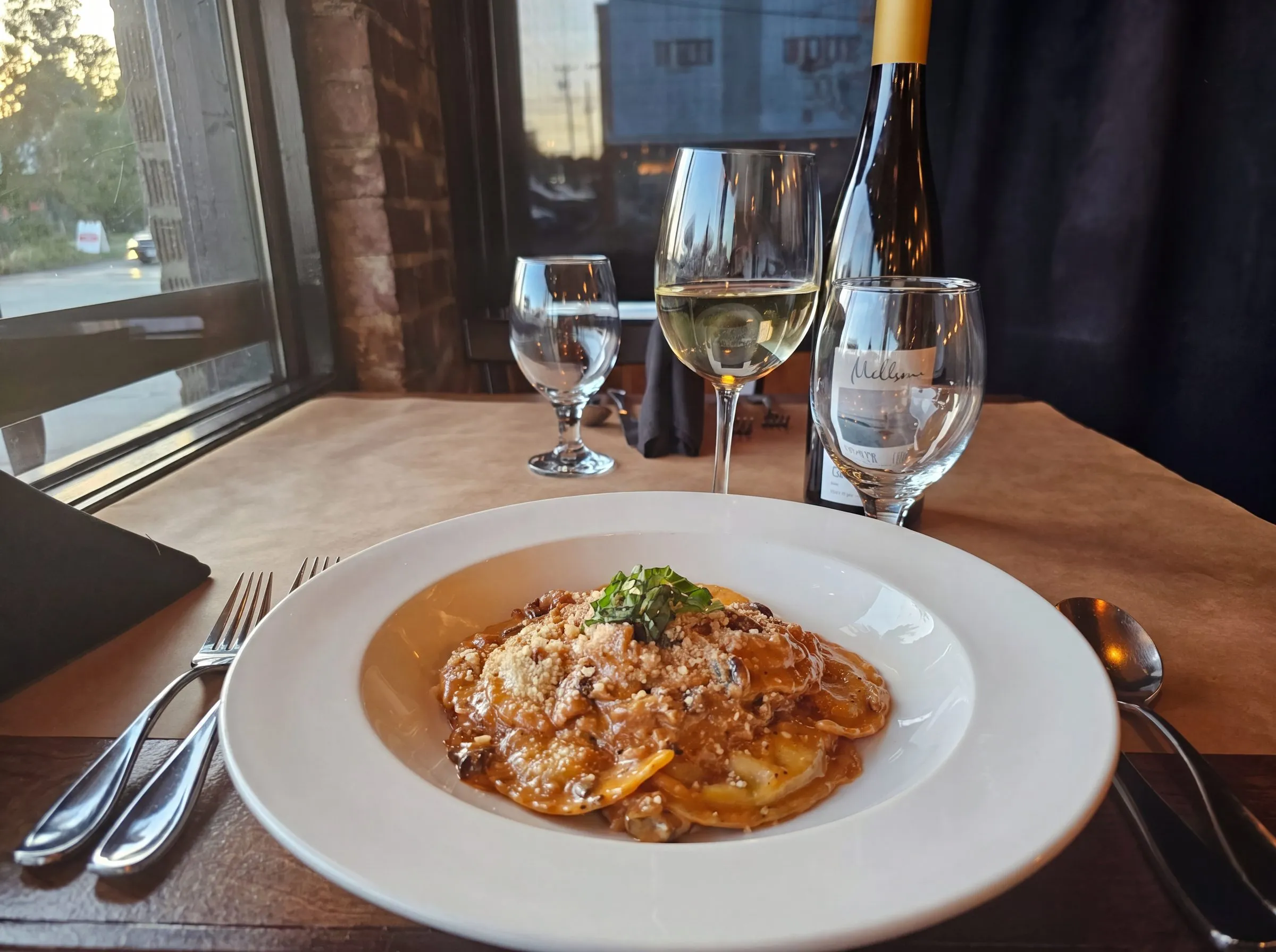 Ravioli in cream sauce at a window table, golden evening light.