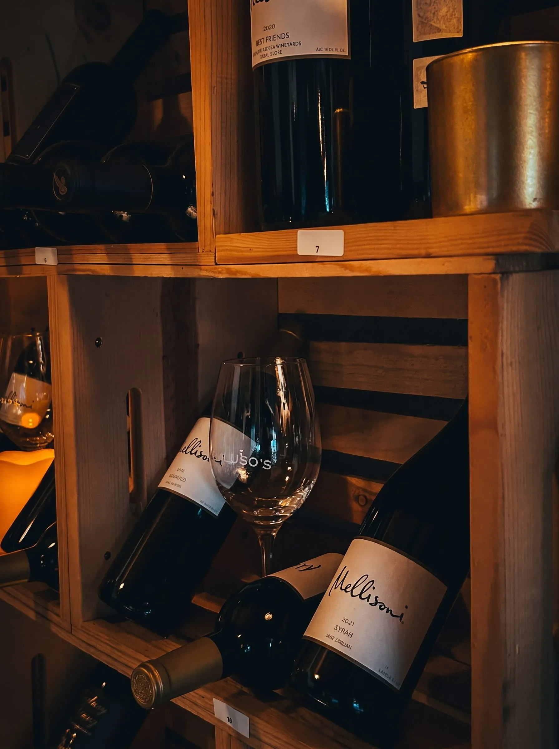 Bottles resting in the wooden crates, a glass etched Macaluso’s in front.